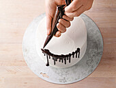 Dripdeko - geschmolzene Glasur mit Spritzbeutel auf den Gebäckrand spritzen