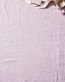 Pink fabric background with Christmas baubles and ribbon