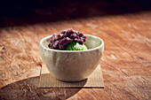 Matcha green tea ice cream topped with sweet azuki beans, traditional Japanese dessert served on ceramic dish