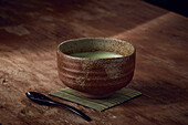 Matcha green tea served in a beautiful traditional Japanese ceramic cup, cozy and warm atmosphere, Japanese tea ceremony style