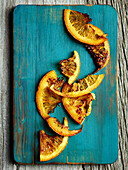 Roasted orange slices on mint-colored wooden cutting board