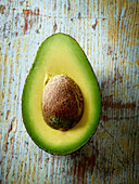Avocado half with pit on wooden background