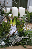 Weihnachtliches Gesteck mit Amaryllis, weißen Kerzen und Glaskugeln