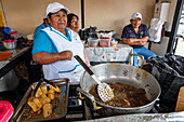 A woman fries whole fish in a street kitchen by the market in Otavalo, Ecuador.