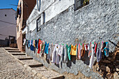 Colorful laundry sways gently above the cobbled sidewalk in the historic center of Caceres, showcasing daily life in Spain.