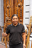 An Amerindian wood carver poses with one of his carved walking sticks for sale on the street in Quito, Ecuador.
