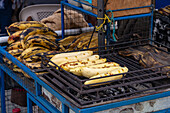 Bananas grilling over charcoal for sale in the open market in Otavalo, Ecuador.