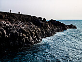 Visitors enjoy breathtaking views at the Los Hervideros cliffs in Lanzarote, looking out over the crashing waves of the Atlantic Ocean.