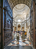Seville, Spain, June 18 2025, Visitors admire the intricately designed main sacristy of Seville Cathedral, framed by a monumental carved door, showcasing rich details.