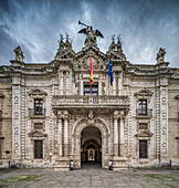 The Rectorate building in Seville features stunning 18th-century baroque architecture, adorned with flags and intricate sculptures.