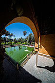 Visitors admire the tranquil Mercury Pond surrounded by lush gardens at the Royal Alcazar, a stunning historic site in Seville.