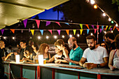 Seville, Spain, June 28 2017, Attendees enjoying drinks at a vibrant bar, celebrating music in an open-air festival setting in Seville during the evening.