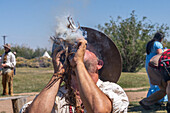 A man in period dress blows on the smoldering tinder for starting a fire with flint and steel at the Fort Bridger Mountain Man Rendezvous in Wyoming.