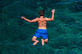 Young people jumping into the sea from a cliff in Polignano a Mare, Puglia, Italy
