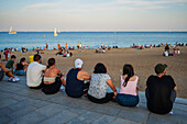 Group of people enjoying Barceloneta beach at sunset, Barcelona, Spain