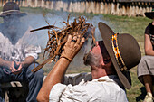 A man in period dress blows on the smoldering tinder for starting a fire with flint and steel at the Fort Bridger Mountain Man Rendezvous in Wyoming.