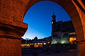 San Martin Church stands majestically as dusk falls, beautifully framed by the arch of Plaza Mayor in Trujillo, Extremadura, Spain.