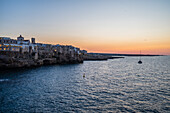 Sailing boat and Polignano a Mare skyline at sunset, Puglia, Italy