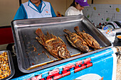 Whole fried fish for sale in a street kitchen by the market in Otavalo, Ecuador.