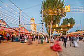 Seville, Spain, Apr 19 2018, Long exposure captures vibrant energy and colorful costumes at the Feria de Abril fair in Seville during the twilight hour.