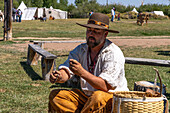 A man in period dress demonstrates starting a fire with flint and steel at the Fort Bridger Mountain Man Rendezvous in Wyoming. Note the sparks above his hand.