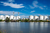 Industrial facilities at the Port of Seville along the Guadalquivir blur into motion, framed by swaying reeds and a bright skyline.