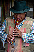 An indigenous Amerindian Quechua man plays the traditional quena or flute in Otavalo, Ecuador.