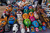 Traditional hand-carved & painted wooden festival masks for sale in the market in Otavalo, Ecuador.