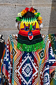 A colorful crocheted Aya Huma mask with traditional poncho for sale in Quito, Ecuador.