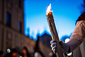 Warm candlelight glows as a penitent holds a candle in Seville, capturing the solemnity of Holy Week at twilight.