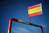 A fishing boat in Ayamonte, Huelva, proudly displays the flag of Spain under a clear blue sky. It's a vibrant coastal scene.