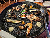 Enjoy a delicious dish of black rice cooked with assorted seafood in Lanzarote, Canary Islands, highlighting local culinary traditions.