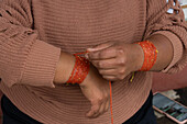 An indigenous woman wraps a traditional bead strand bracelet in Otavalo, Ecuador.