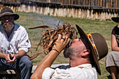 A man in period dress blows on the smoldering tinder for starting a fire with flint and steel at the Fort Bridger Mountain Man Rendezvous in Wyoming.
