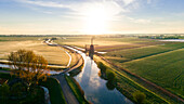 Drohnenansicht einer klassischen holländischen Windmühle bei Sonnenaufgang mit Nebel, Frühling in Holland, die Niederlande