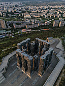 Luftaufnahme des Denkmals der Chroniken von Georgien, einer markanten Struktur aus dunklen Steinsäulen vor dem Hintergrund der Stadtlandschaft von Tiflis, Tiflis, Tiflis, Georgien.