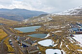 Aerial view of reflective lakes mirroring the sky, nestled amidst snow-dusted mountains and rugged terrain, a serene contrast of cold and warmth, Butha-Buthe, Lesotho.