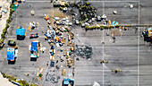 Aerial view of scattered debris and makeshift shelters create a stark contrast on the pavement, revealing a story etched in the landscape of Valencia, Valencian Community, Spain.