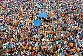 Aerial view of a bustling cattle market with vibrant colors, dense crowds, and brown cows under blue tarps, Mahasthan, Rajshahi Division, Bangladesh.