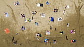 Aerial view of sunbathers scattered like vibrant confetti across the textured sands, where the azure sea meets the shore, Split, Split-Dalmatia County, Croatia.