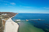 Luftaufnahme der langen Seebrücke, die vom Sandstrand der Seebrücke Sellin in das türkisfarbene Meer hineinragt, Sellin, Mecklenburg-Vorpommern, Deutschland.