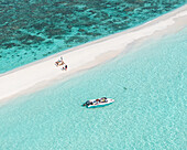 Aerial view of a pristine white sandbar stretching into a turquoise lagoon with corals, where a boat glides and figures relax, Thoddoo, Alif Alif Atoll, Maldives.