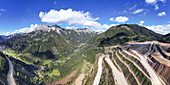 Luftaufnahme der zerklüfteten Berge, die auf die Stufenterrassen des Erzbergwerks treffen, ein starker Kontrast zwischen Natur und Industrie, Eisenerz, Steiermark, Österreich.