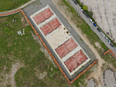 Aerial view of the tennis courts with their vibrant red surfaces and precise white lines, framed by a stark concrete border, Batumi, Adjara, Georgia.