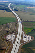 Aerial view of a scenic highway surrounded by agricultural fields and power lines, Panketal, Brandenburg, Germany.