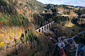 Aerial view of a picturesque autumn landscape featuring a bridge over a valley surrounded by colorful foliage and serene woods, Freiburg, Baden-Wurttemberg, Germany.