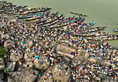 Aerial view of bustling raw jute market with traditional wooden boats and vibrant community activity along the river, Chinadulli, Islampur, Mymensingh, Bangladesh.