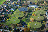 Aerial view of a water plant surrounded by circular structures and residential areas with autumn trees, Klarahoh, Lindenberg, Brandenburg, Deutschland.