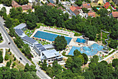 Luftaufnahme von luxuriösen Swimmingpools, umgeben von Grün und Bäumen in einem lebendigen Ferienort, Roth, Bayern, Deutschland.
