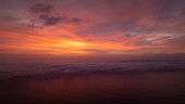 Aerial view of serene sunset over coastal Seal Island with dramatic clouds and tranquil water, Muizenberg, Western Cape, South Africa.